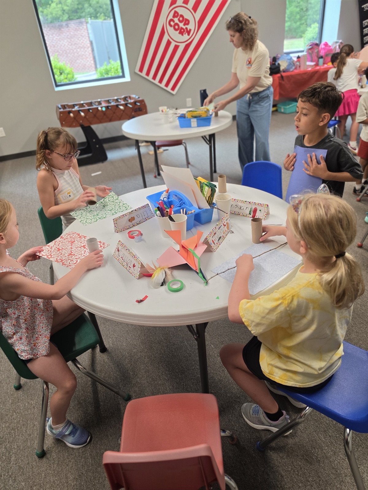 Campers create paper crafts together around an activity table