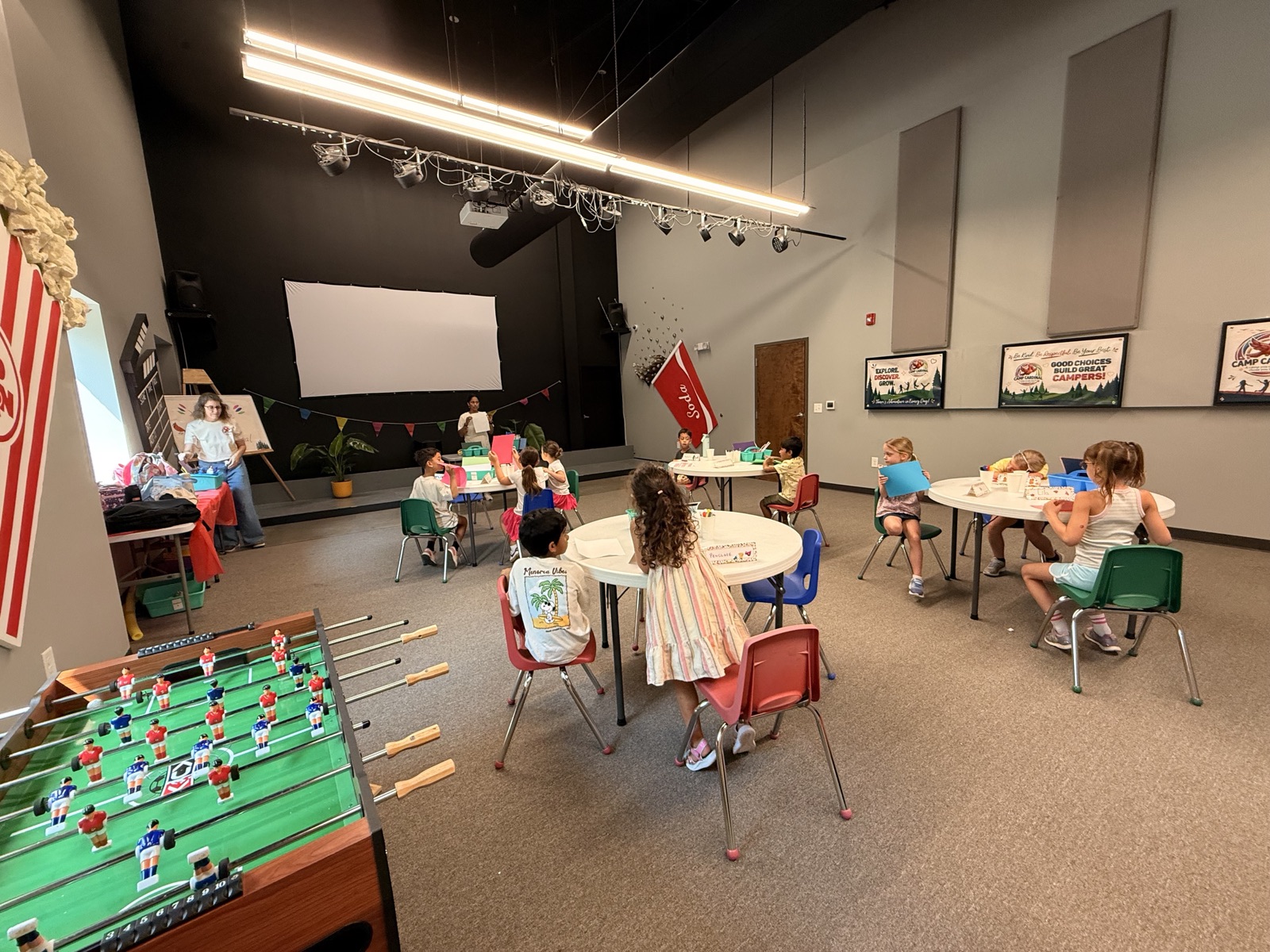 Campers gather around activity tables in the Camp Cardinal room