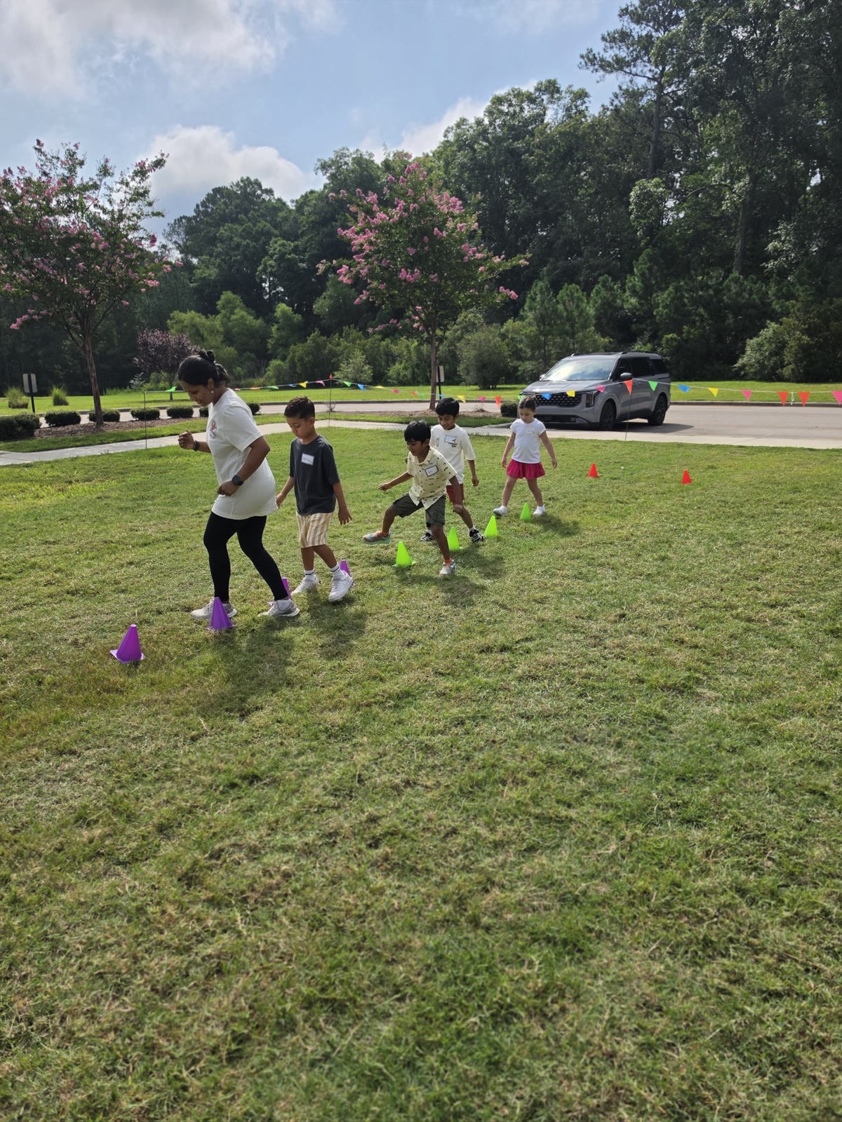 Campers follow a counselor through a cone course on the grass